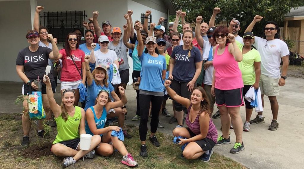 Bisk team giving back to the community - smiles and cheers outside of house they painted
